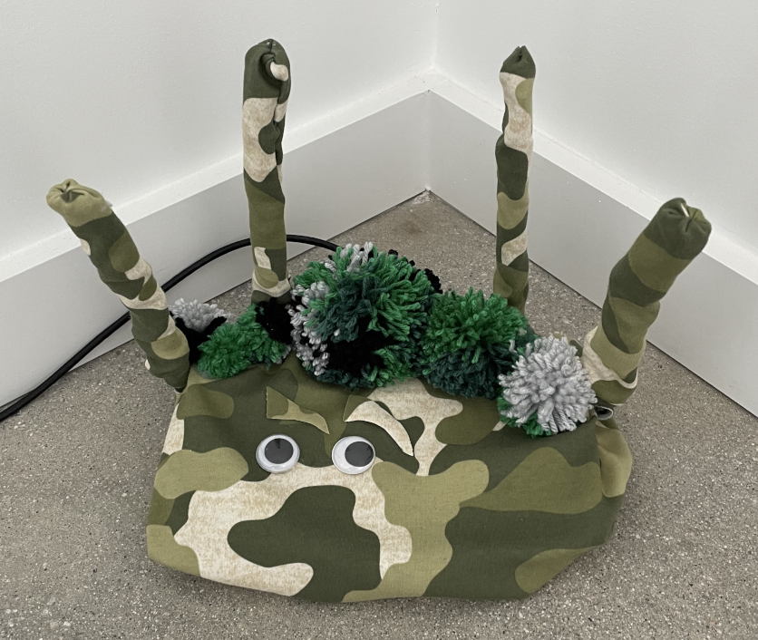 Photo of a wifi router covered with fabric in camouflage pattern with googly eyes